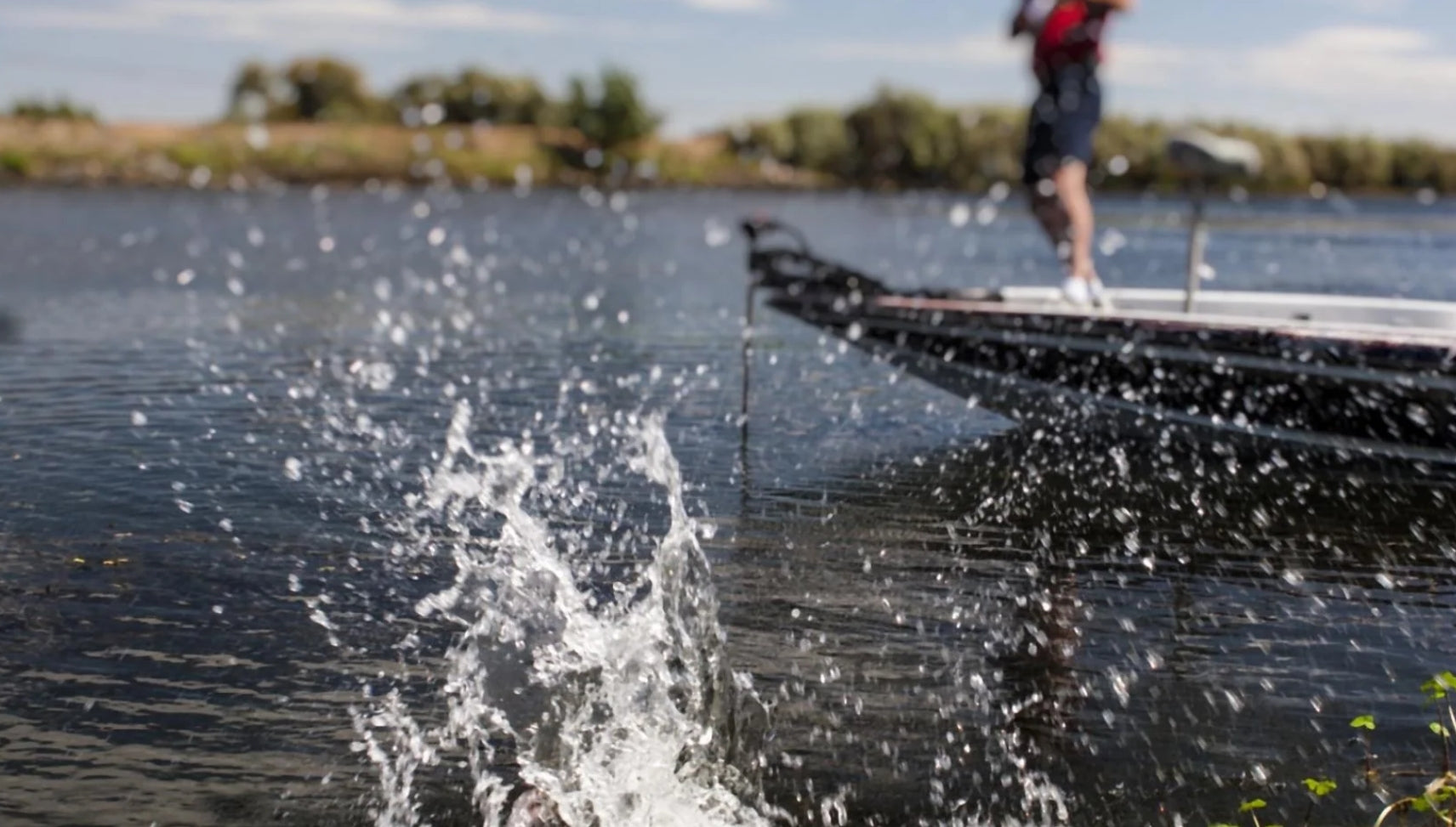 Fishing jumping in water next to boat